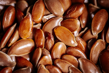 A macro photograph of shiny brown flax seeds showcasing their smooth texture and natural luster. The seeds are tightly packed, highlighting their details and rich tones.