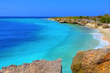 Paradise empty beach with turquoise sea water, small waves and rocks. Tropical shoreline, empty ocean. Sandy shore with stones and blue water surface.