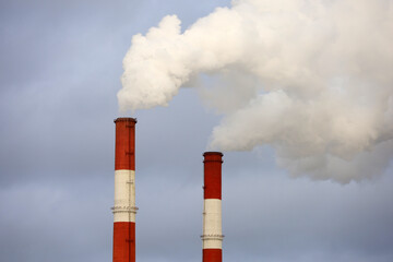 Smoking pipes on cloudy sky background. Concept of steam plant, air pollution, heating season or...