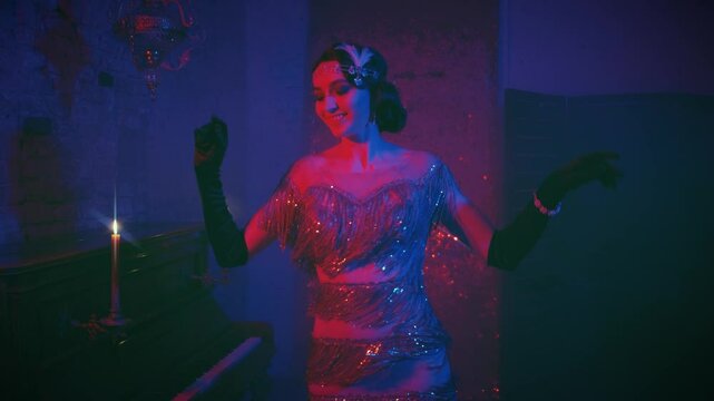 Young beautiful happy retro woman dancer smiling beauty face, shining luxury sexy gold dress, finger wave hairstyle dancing in dark room pink blue purple neon light. Vintage old 20s retro style party