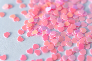 Romantic Tenderness: Heart-shaped confetti in soft pink hues is scattered chaotically on a white background.  Each heart serves as a reminder of the beauty in simple moments filled with love and care.