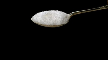 Super slow motion of sugar pouring from a silver spoon