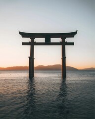 A majestic Torii gate stands alone in the calm waters of a lake, silhouetted against a vibrant sunset sky.