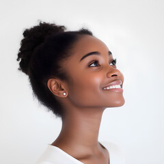 Profile portrait of a young black woman with her hair tied up and smiling. Her head is tilted slightly upward. Natural light. She wears minimal makeup and an earring, white background