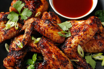 Grilled chicken wings with bbq sauce in a black plate