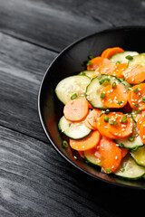 Asian style cucumber and carrots salad with sesame seeds, sweet and sour dressing and spring onions