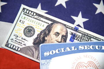 Social Security Card and Hundred dollars bill close up shot with American flag in the backdrop. USA...