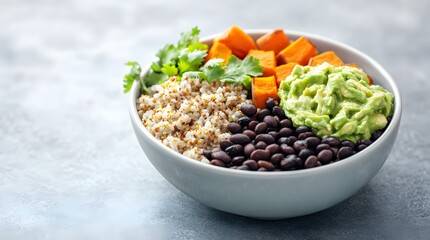 A colorful bowl filled with quinoa, black beans, roasted sweet potatoes, guacamole, and fresh cilantro on a light background.
