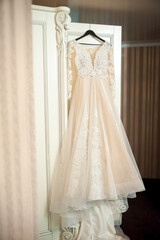 Fototapeta premium Bridal suite with elegant dress. A stunning wedding dress hangs in the bridal suite, highlighting delicate lace and soft fabric details.