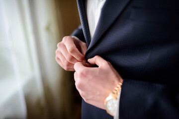 Obraz premium Groom adjusting his suit before ceremony. A groom adjusts his suit while preparing for the wedding ceremony, showing focus and elegance in the moment.
