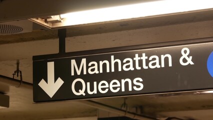 New York subway station interior, Manhattan text sign. Underground metropolitan. United States metro transport navigation. Information signage public passenger railway. Downtown and Queens direction.