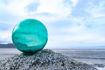 Glass ball on top of a boulder on the seashore, minimalism