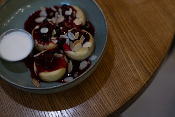 cottage cheese pancakes with almond flakes and cherry jam on a plate on the table
