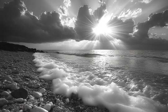 Sunbeams shine over a rocky beach with waves