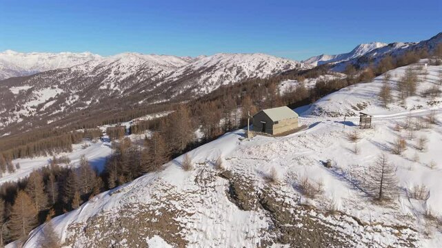 Aerial drone film snow covered mountain peaks with small chapel with cross on slope cliff in Italy