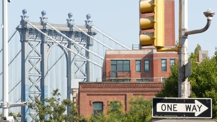 Obraz premium New York City Manhattan Bridge view from Brooklyn Bridge. Red brown brick residential building windows. Classic NYC architecture. United States real estate. Traffic light. One way arrow road sign.