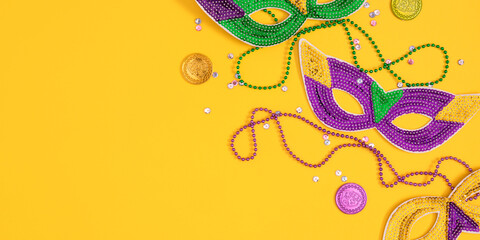 Top view of a beautiful composition of colorful masks, confetti, Mardi Gras decorations. Yellow Mardi Gras banner. Mardi gras holiday background © prime1001