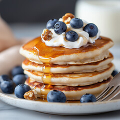 A delicious stack of blueberry pancakes with a glass of milk and whipped cream topping. 