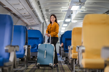 Fototapeta premium Woman Boarding Airplane: A joyful woman in a stylish outfit confidently walks down the aisle of an airplane with her luggage, ready for her exciting journey.