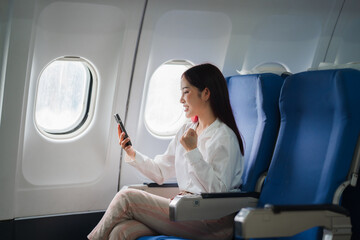 Flight of Joy: A young woman celebrates a milestone, beaming with happiness while looking at her phone on an airplane.
