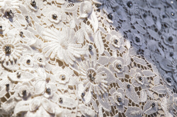 Texture of white lace with rhinestones. Delicate silk lace decorated with flowers and crystals