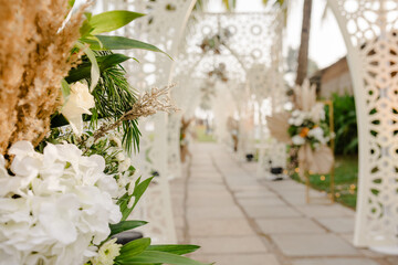 A romantic white beach wedding celebration with an outdoor ceremony, featuring elegant decor, a bottle for colored sand rituals, and a beautifully arranged table under the open sky