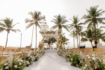 Fototapeta premium A romantic white beach wedding celebration with an outdoor ceremony, featuring elegant decor, a bottle for colored sand rituals, and a beautifully arranged table under the open sky