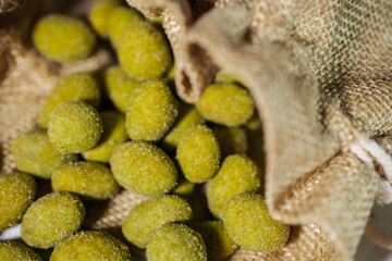 Close-up of vibrant yellow-green wasabi-coated nuts spilling out of a rustic burlap sack. Coated in a fine powder, they appear crunchy and flavorful.