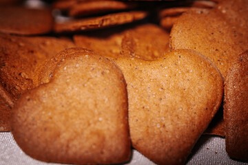Close-up of freshly baked heart-shaped gingerbread cookies with a golden brown color stacked together on a light surface. Warm and festive atmosphere.