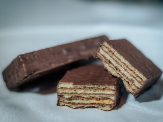 A detailed view of chocolate-covered wafer bars, showcasing their crispy, flaky texture and rich cocoa coating, arranged against a soft fabric backdrop.