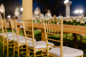 A romantic white beach wedding celebration with an outdoor ceremony, featuring elegant decor, a bottle for colored sand rituals, and a beautifully arranged table under the open sky