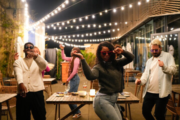 Multiethnic friends dancing together at rooftop party