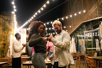 Friends dancing together at night in a trendy outdoor venue