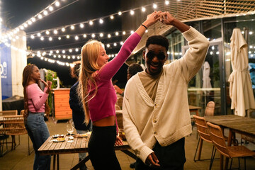 Young multiethnic friends dancing at rooftop party