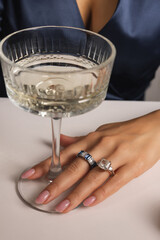 Elegant woman in evening black dress with jewelry and rings, holding a champagne glass, celebrating Christmas and New Year's with red caviar. sensual girl eating tangerine.