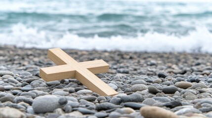 Fototapeta premium Wooden cross resting on pebbles by the ocean shore.