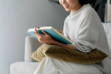 Happy young woman reading book at home, relaxation and leisure