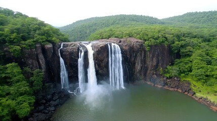 Obraz premium A scenic waterfall cascading into a tranquil pool surrounded by greenery.