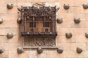 Historic window with ornate wrought iron grill on a stone building in Salamanca, Spain