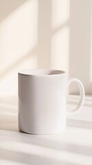 White porcelain mug standing on a white table, illuminated by natural window light creating beautiful shadows, perfect for showcasing designs