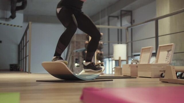 Girl exercising on balance board in fitness studio..