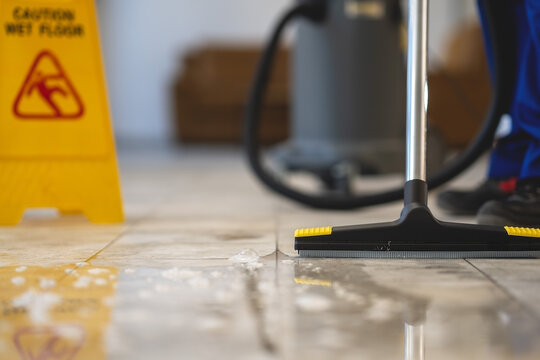 Professional removing water from the floor with a vacuum cleaner