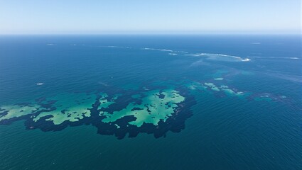 Aerial view of oil spill on ocean creating contrast with clear surrounding water
