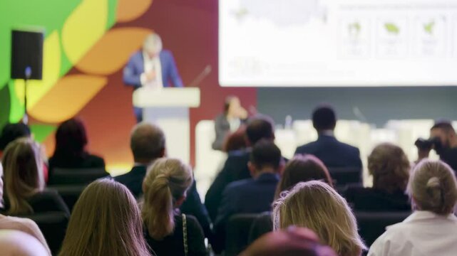 Professional audience attentively listening to a keynote speaker at a modern business conference.