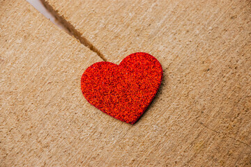 A heart-shaped object resting on a rustic wooden surface, symbolizing love and warmth. The wood&rsquo;s natural texture contrasts with the smooth, vibrant heart. Soft lighting enhances the cozy, romantic 