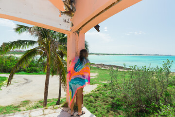 young girl standing inside of an old abandoned building and looking toward the ocean, vacation travel background