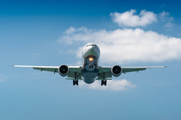 A blue sky background with an airplane prepared for landing on a well known place for plane spotter at Mao Khao Beach, Phuket, Thailand