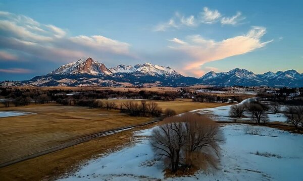 Scenic Winter Landscape Featuring Snow-Capped Mountains, Open Fields, and a Serene Sunset Sky with Soft Clouds, Showcasing Natural Beauty and Tranquility