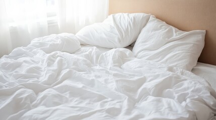 Unmade bed with crumpled white bedsheet and pillows after sleeping with morning sunlight shining through the window, creating a cozy and relaxed atmosphere