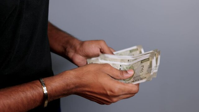 Counting indian five hundrend rupees note in black tshirt